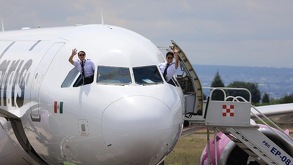 Avión en la pista de vuelo de la aerolínea Volaris con los pilotos saludando