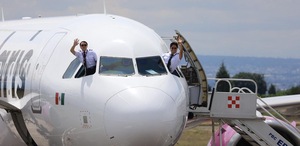Avión en la pista de vuelo de la aerolínea Volaris con los pilotos saludando