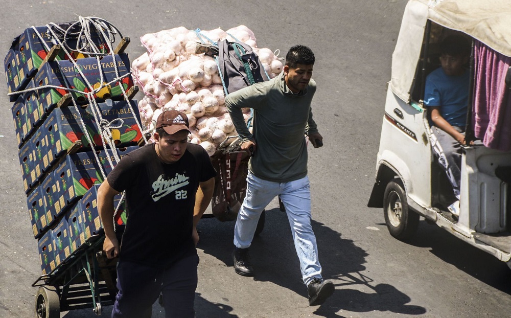 Hombres cargando mercancía afuera de la Central de Abasto.