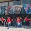Se observa a varias personas que visten playera roja y están de pie.