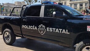 Vista lateral de una patrulla de la Policía del Estado de Jalisco con el logotipo de la dependencia grabado en las puertas