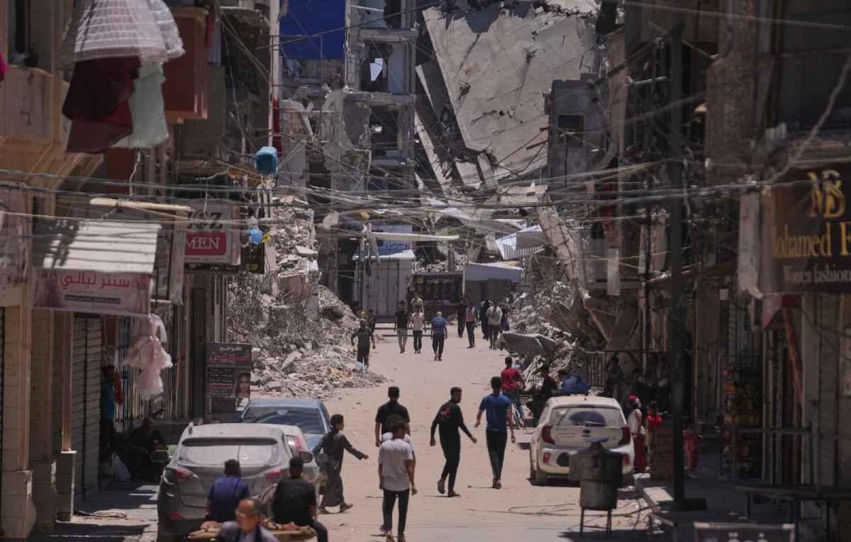 Varios palestinos caminan por una calle rodeada de edificios destruidos por ataques del ejército israelí durante la guerra entre Israel y Hamás en Jan Yunis.