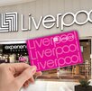 Aspecto de una tienda Liverpool en México, con una mano sobrepuesta cargando una tarjeta de la tienda.