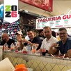Grupo de varias personas sentadas en la barra de un puesto de tacos dentro de un mercado en Guadalajara