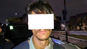 Hombre con los ojos y parte del rostro censurada por un recuadro blanco al ser detenido delante de una patrulla de la Policía de Guadalajara