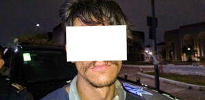 Hombre con los ojos y parte del rostro censurada por un recuadro blanco al ser detenido delante de una patrulla de la Policía de Guadalajara