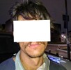 Hombre con los ojos y parte del rostro censurada por un recuadro blanco al ser detenido delante de una patrulla de la Policía de Guadalajara