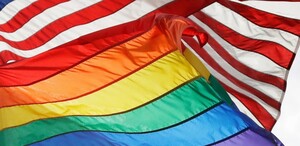 Una bandera LGBTQ+ ondea tras una bandera estadounidense en el monumento nacional de Stonewall en Nueva York, el 11 de octubre de 2017