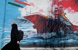 Una mujer pasa junto a un mural que muestra un portaaviones estadounidense bajo ataque en el centro de Teherán, Irán, el lunes 8 de junio de 2026.