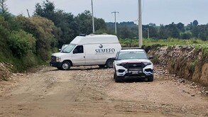 Patrulla de policía y Semefo estacionados en campos de cultivo.