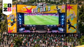 Pantalla gigante transmitiendo un partido del Mundial con carteles del evento Jalo Futbolero en Michoacán y público en el sitio