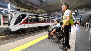 Personal de seguridad de Siteur con una persona en silla de ruedas en una estación del Tren Ligero en Guadalajara