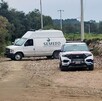 Patrulla de policía y Semefo estacionados en campos de cultivo.
