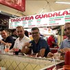 Grupo de varias personas sentadas en la barra de un puesto de tacos dentro de un mercado en Guadalajara