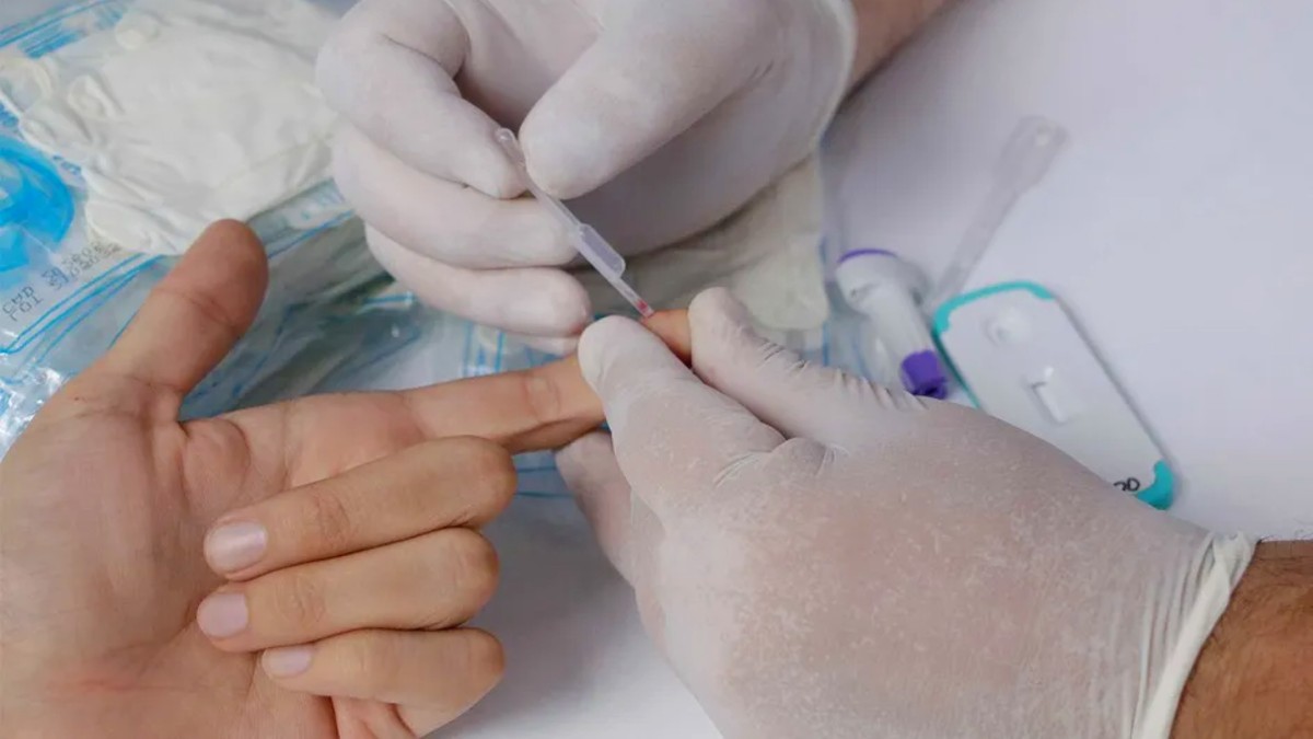 Mano de un persona con el dedo extendido realizándose una prueba de ITS con la extracción de una muestra de sangre con guantes médicos alrededor