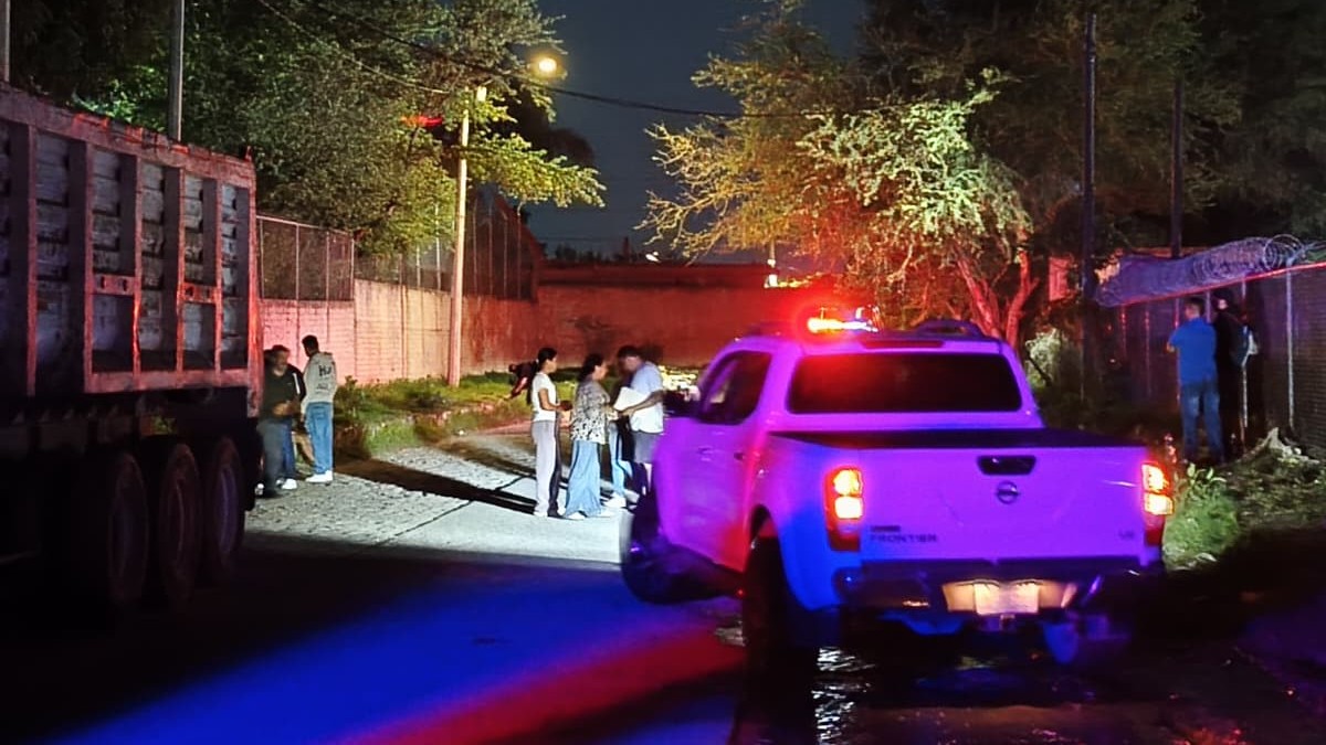 Personas reunidas en el lugar donde ocurrió un accidente de cuatrimoto con una patrulla de la Policía de Tlaquepaque estacionada detrás de ellos