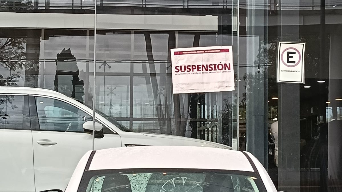 Anuncios de suspensión de Profeco y enfrente automóviles de la agencia Mazda