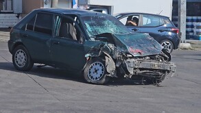 Automóvil color verde destruido del crista y de la parte frontal tras chocar contra camión con una Farmacia Guadalajara detrás