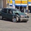 Automóvil color verde destruido del crista y de la parte frontal tras chocar contra camión con una Farmacia Guadalajara detrás