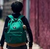 Niño con una mochila caminando hacia una escuela.
