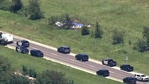 Vista aérea de lugar donde se desplomó una avioneta de paracaidismo en Misuri con patrullas y automóviles circulando en la carretera de un costado