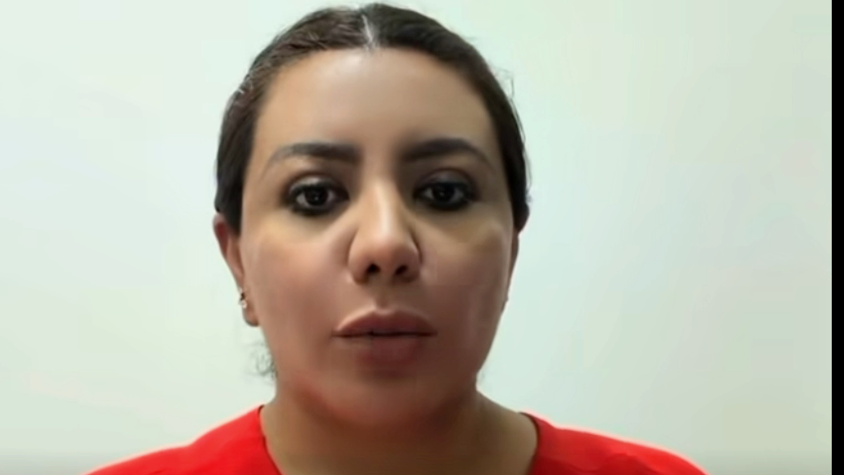 Mujer vestida de color rojo hablando ante una cámara.