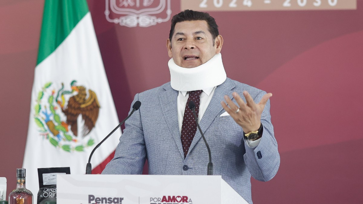 Hombre con collarín hablando ante un micrófono.