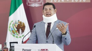 Hombre con collarín hablando ante un micrófono.
