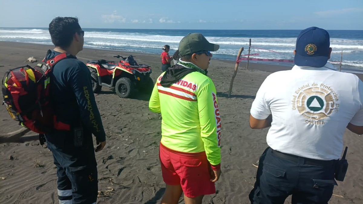 Guardavidas y elementos de Protección Civil y Bomberos de Colima resguardando un área acordonada a la orilla de una playa con una cuatrimoto