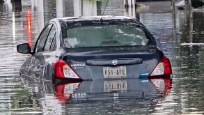 Automóvil Nissan Versa color azul atrapado en medio de una inundación en calles de Zapopan