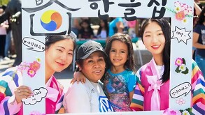 Dos mujeres coreanas vistiendo trajes típicos de Corea y sosteniendo un marco para fotos junto con una madre mexicana y su hija durante el KocuFest en Zapopan