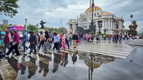 Peatones realizan una fila para evadir un espejo de agua frente al Palacio de Bellas Artes.