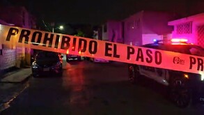 Se observa una cinta amarilla de precaución, es de noche y hay una patrulla.
