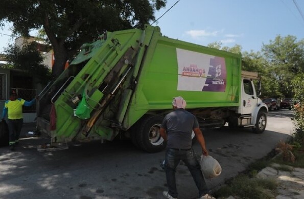 Se observa un camión de basura y dos hombres a lado de éste.