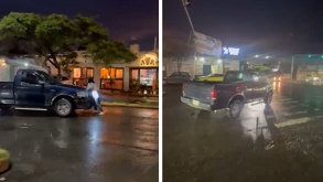 una mujer se aferra a la parte delantera de una camioneta en medio de una calle