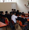 Se observa a varios niños sentados en pupitres en un salón de clases.