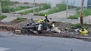 Motocicleta tumbada sobre tierra y hojas al lado de una banqueta con un tenis nike y parte del vehículo a un costado