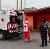 Se observa una ambulancia en color rojo y balnco y unas personas en medio de la calle.