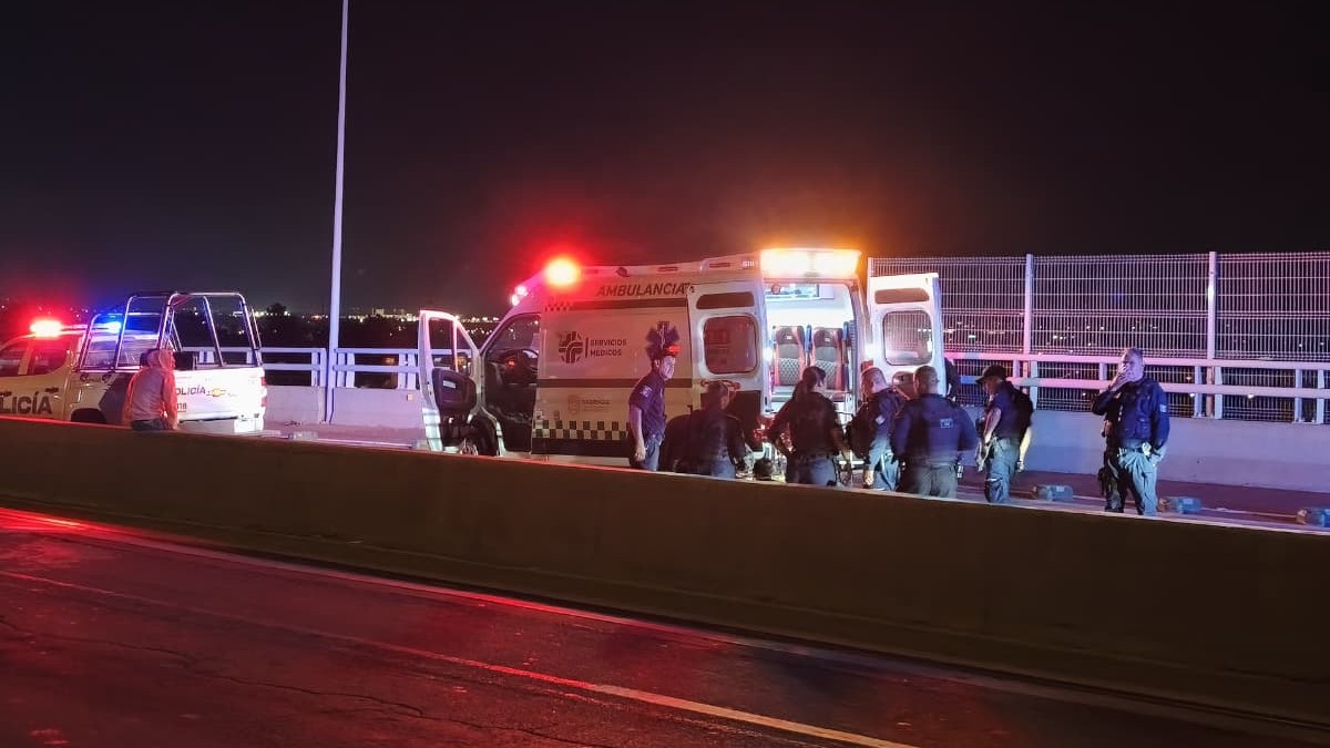 Patrulla y policías de Tlaquepaque junto con paramédicos y una ambulancia de la Cruz Verde en medio de una carretera atendiendo un lesionado