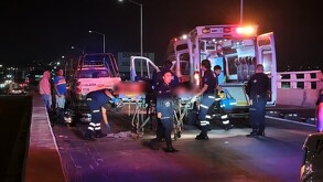 Paramédicos de la Cruz Verde llevando a un hombre herido hasta una ambulancia con policías de Tlaquepaque y personas alrededor