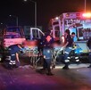Paramédicos de la Cruz Verde llevando a un hombre herido hasta una ambulancia con policías de Tlaquepaque y personas alrededor