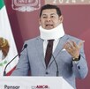 Hombre con collarín hablando ante un micrófono.