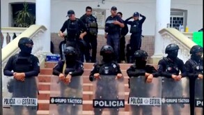 Policías cuidando la entrada a un edificio.