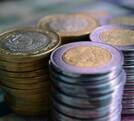 varias pilas de monedas de cinco y 10 pesos mexicanos