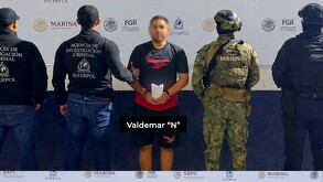 Valdemar 'N' con la cara censurada con blur en medio de agentes de la Interpol y militares de la Marina y la Secretaría de Seguridad durante su detención