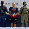 Valdemar 'N' con la cara censurada con blur en medio de agentes de la Interpol y militares de la Marina y la Secretaría de Seguridad durante su detención
