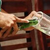 Persona sirviéndose una botella de cerveza en un vaso.