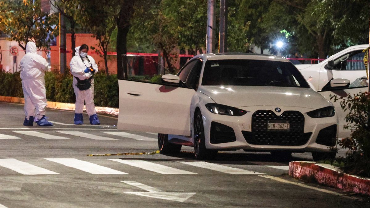 Peritos investigan asesinato de un hombre en su auto.