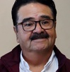 Hombre adulto con bigote sonriendo.
