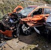 Camioneta Mercedes Benz color naranja completamente destruida del frente tras chocar contra otra camioneta color blanco